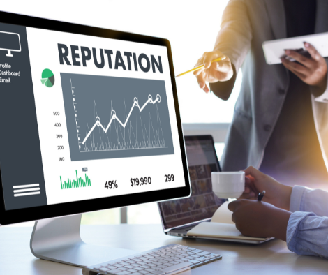 Image of a computer monitor showing a graph of a brand reputation growing and two people discussing it.