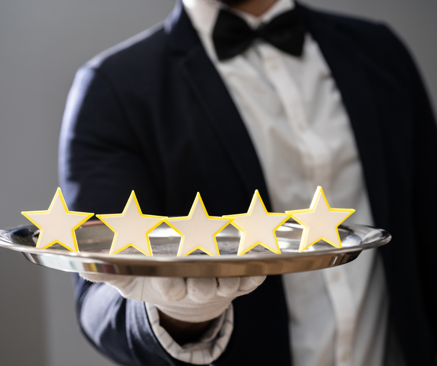 Picture of a waiter holding up a tray with 5 stars on it.