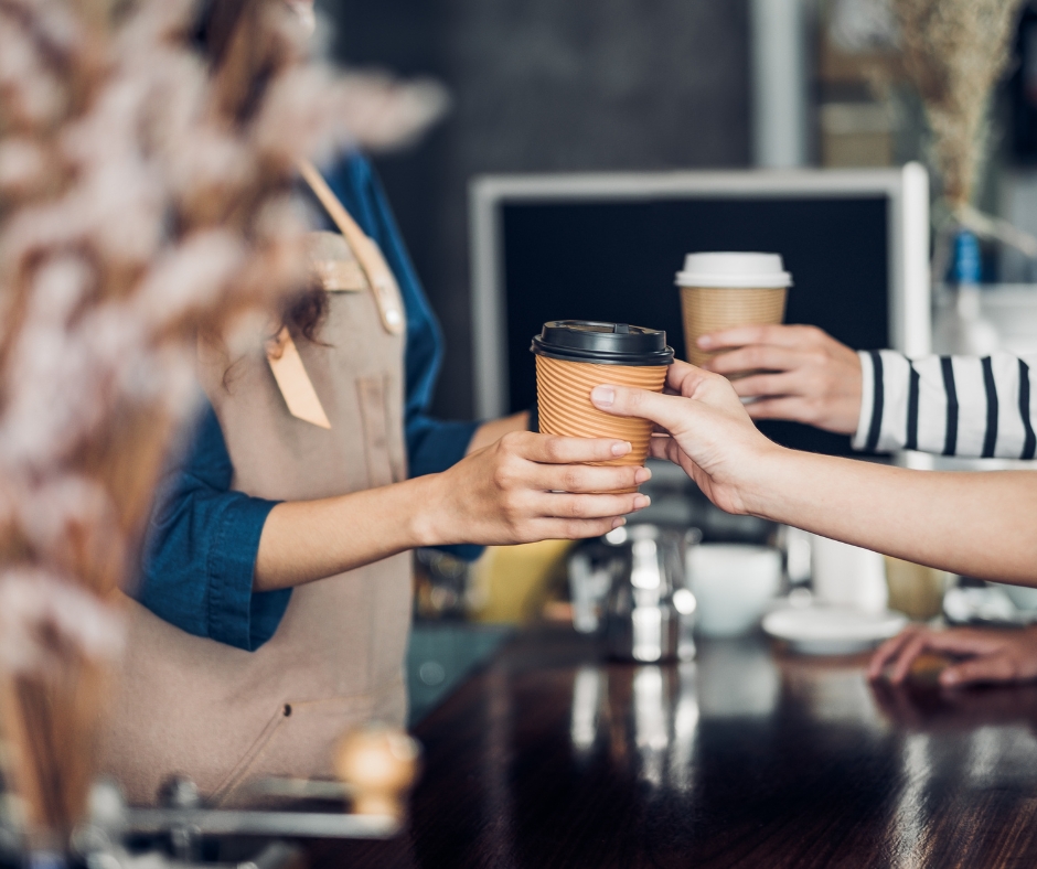 image depicting someone receiving their order at the counter of a coffee shop