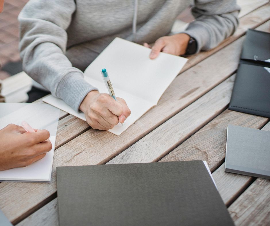 two people writing down things from files in front of them