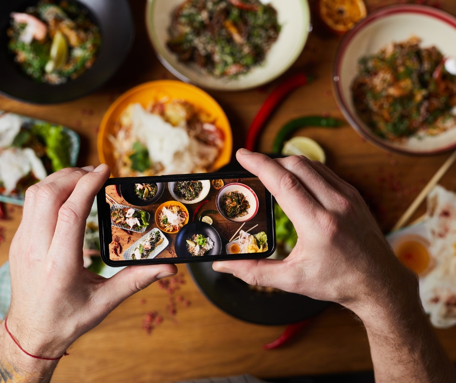a picture of someone taking a picture of food at a restaurant as an example of user-generated content