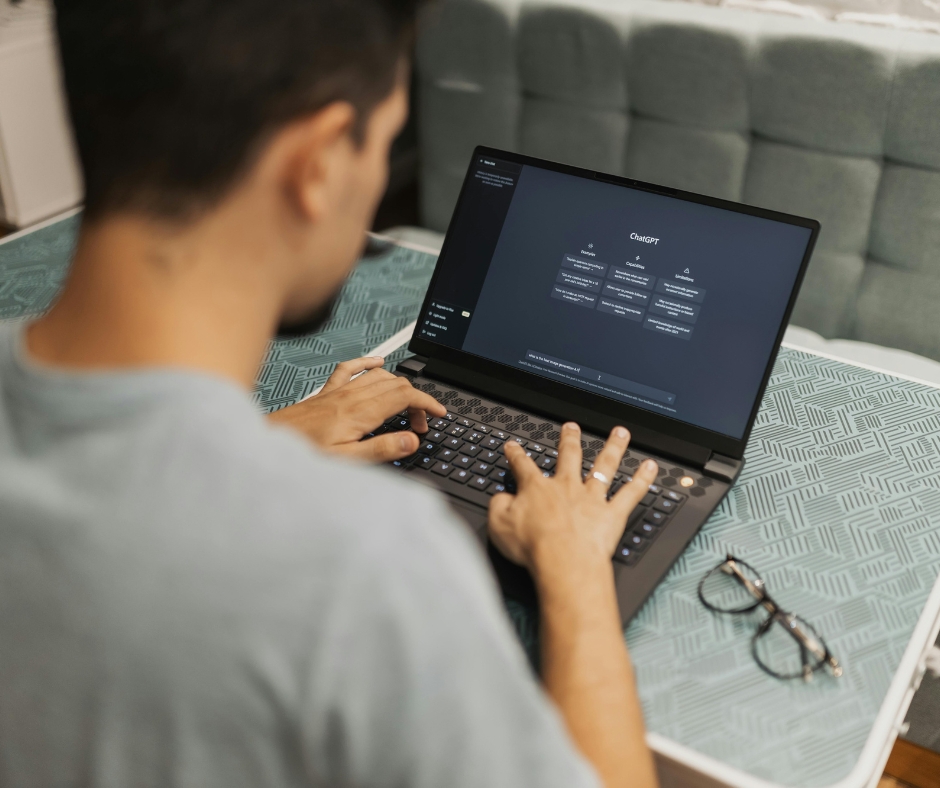 picture of the back of a man sitting at a laptop and using an AI software to ask a question
