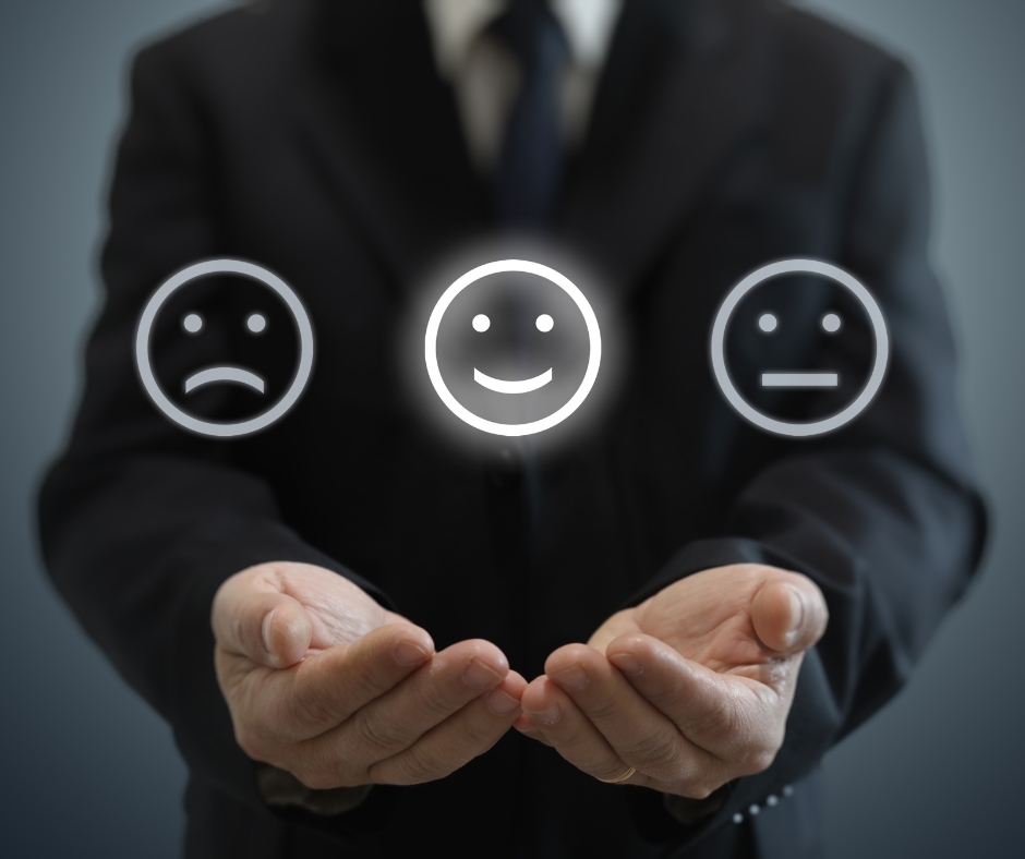 image depicting a man in suit holding his palms in front of him and above them are 2 faces: sad, smiley, and neutral. smiley face is in the middle and highlighted
