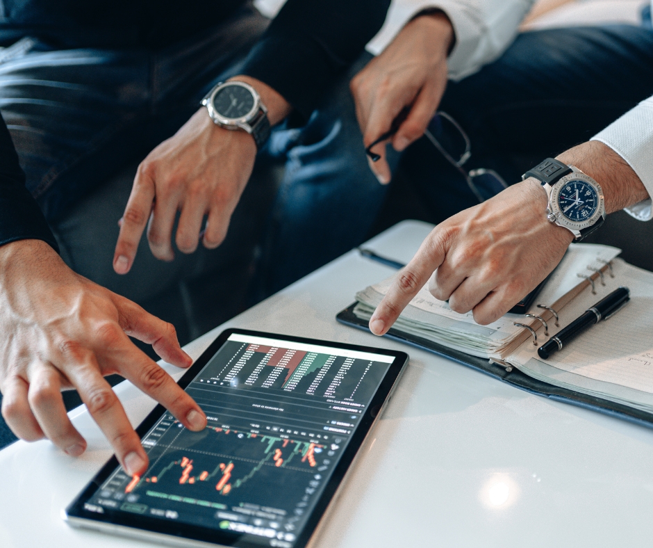 image showing 2 people looking at data on a tablet and taking notes in an agenda